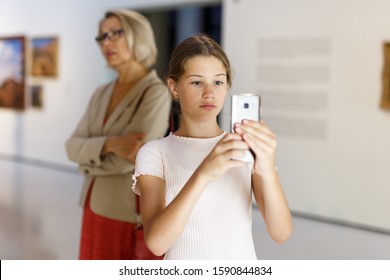 Tween Girl Visitor Using Phone In Paints Exposition At Museum