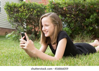 Tween Laying In The Grass With A Cell Phone