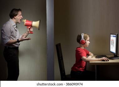 Tween Son In Headphones Looks At A Computer Screen While His Father Yells At Him Through A Megaphone