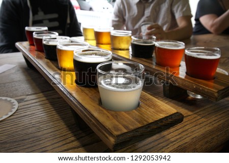 Twelve beer samples being shared at a table by some men.