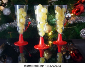 Twelve grapes in the glasses. Selective focus, Christmas tree background. Traditional Spanish to eat twelve berries for good luck at midnight. New Year's Eve.