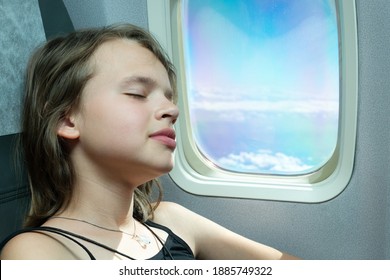 Twelve-year-old girl sleeps near the window of the plane during the flight - Shutterstock ID 1885749322
