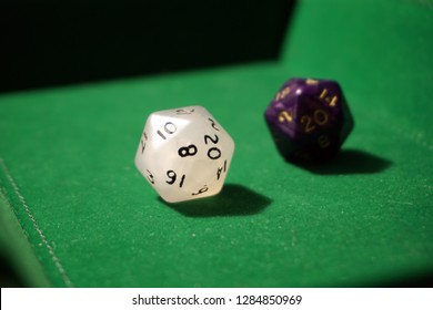                     Twenty sided dice on green felt. A white twenty sided die on focus and another purple die blurred behind it. Used for role playing games like Dungeons and Dragons.