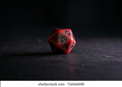 A twenty sided  polyhedral die on a slate surface. These type of dice are used for role playing games.