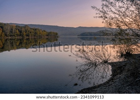Twilight landscape. A lake with a mirror surface of water and an autumn forest on the shore. Soothing landscape.