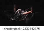 In the twilight of a summer day, can see a saddle and horse ammunition, dressed on a black horse. Equestrian sports and horse riding.