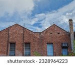 Twin Arched Rooflines on an Old Brick Building with Rain Showers Above.