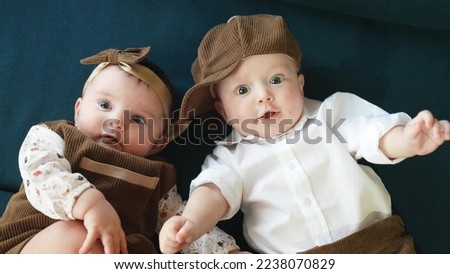 twin babies in retro clothes. brother and sister a twins kids sit on the couch in retro clothes cap play among lifestyle themselves. happy family kid dream twin concept