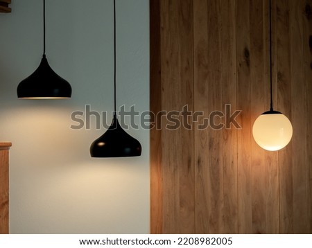 Twin ceiling lighting in the dark room. Two hanging lamp or round ceiling lamp decorated as a steps and round light full moon shape on white and wood wall.