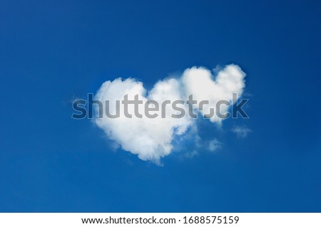 twin clouds shaped heart on bright blue sky.