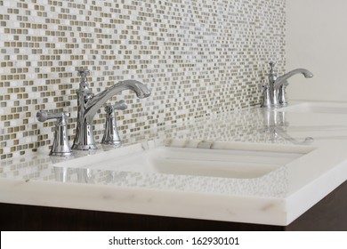 Twin Contemporary Bathroom Sinks With Chrome Fixtures, Against A Mosaic Tile Wall.