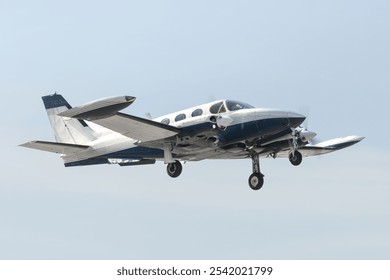 Twin Engine Aircraft during climb out.  Blue and white multi with retractable gear and two propellers departs the airfield for bluer skies. Isolated airplane flying overhead - Powered by Shutterstock