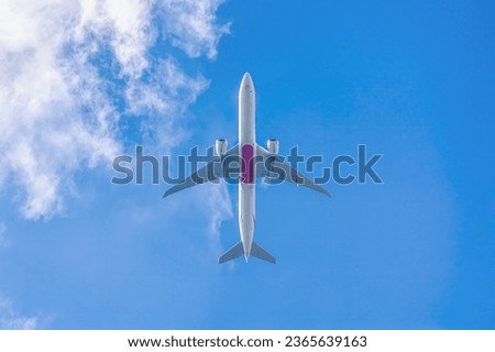 Twin engine passenger plane high in blue sky with clouds view from below