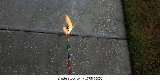 Twin Flames From A Colorful Sparkler Over Sidewalk At Night