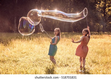 Twin Girls Make Big Soap Bubbles In The Park