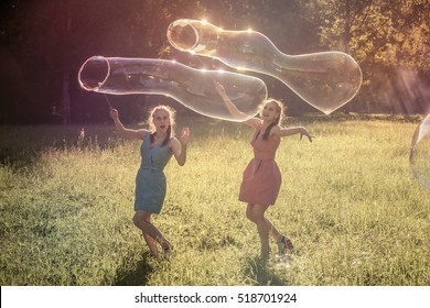 Twin Girls Make Big Soap Bubbles In The Park