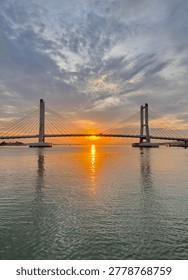 Twin Pylon Cable Stayed Bridge Over Sea at Sunset with Perfect Water Reflection
Wide view of a modern cable stayed bridge with two tall pylons spanning over calm sea during golden sunset. Symmetrical composition with sun positioned between pylons and perfect reflection on water surface.