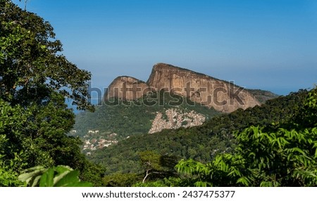 Twin rock formations tower over Rio's largest favela, Rocinha, amid lush greenery.