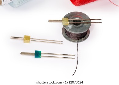 Twin Sewing Machine Needles Different Size And Metal Bobbin With Black Threads Close-up On A White Background 
