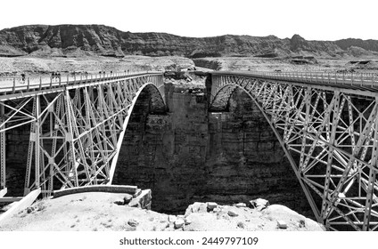 Twin spandrel arch bridges spanning over Marble Canyon and Colorado river. New and historic “Navajo Bridge“, unique steel constructions from 1929 and 1995. Black and white panorama with both bridges. - Powered by Shutterstock