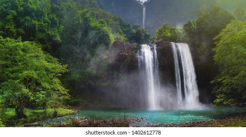 Twin Waterfall Rain Forest In Valley Like A Paradise Garden With Turquoise Pond and Blur Waterfall  Mountain Behind. Curug Sodong in Geopark Ciletuh with Cataractagenitus Cloud From Water Splash - Shutterstock ID 1402612778
