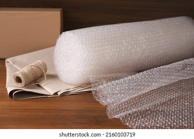 Twine, paper and roll of bubble wrap on wooden table - Shutterstock ID 2160103719