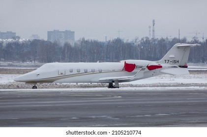 A Twin-engine Jet Plane Covered With Snow Stands At The Airport In The Parking Lot