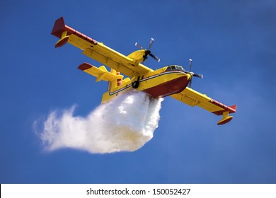 A twin-engined water bomber dumping its load
