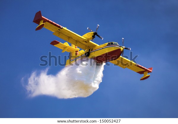 A twin-engined\
water bomber dumping its load