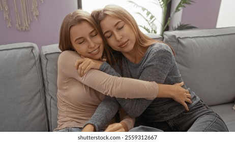 Twins embrace lovingly on a couch, highlighting sisterly bond, blonde hair, and serene, homey atmosphere in a cozy living room setting with soft light. - Powered by Shutterstock