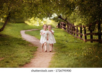 Twins Girls Run Barefoot On The Road In A Summer Park.
Image With Selective Focus, Noise Effects And Toning. Focus On The Girls.