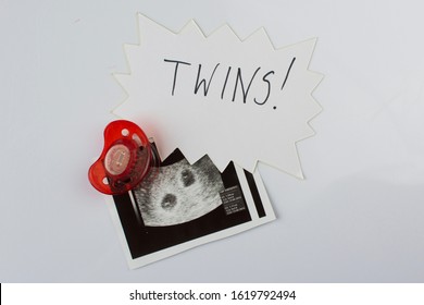 Twins Ultrasound Picture And A Red Soother. 