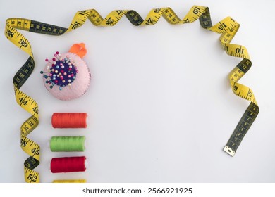 Twisted Measuring tape and color spools of sewing thread and straight Pins against white background with copy space - Powered by Shutterstock