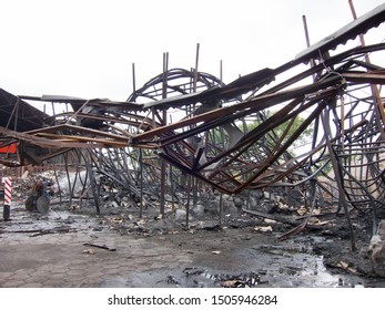 Twisted Steel Beams After A Factory Fire. Warehouse Destroyed By Fire. Twisted Metal, Pile Of Burnt Rubble.