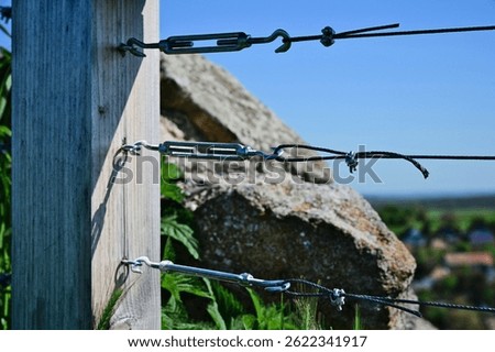 twister wire steel cable railing. galvanized metal tension turnbuckle. closeup view. connection and tightening hardware device. rail guard detail. modern twisted wire rope design