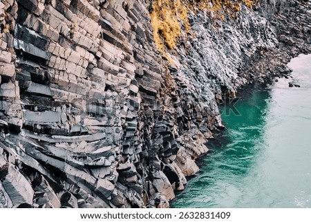 Twisting basalt columns meet turquoise waters in Studlagil Canyon, Iceland.
