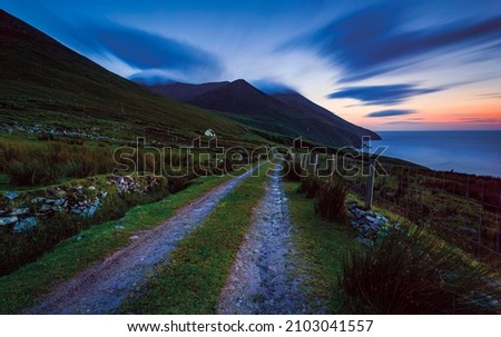 Twisty road in Connemara Moutains at sunset, Ireland Typical Ireland - Coast, green grass, blue skies, clouds, rain coming, rainbow. Beautiful, amazing, breathtaking.