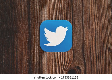 Twitter app blue logo with bird printed on paper centrally placed on wooden background. SWANSEA, UK - MARCH 11, 2021