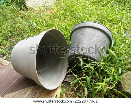 Two abandoned small plastic vases on ground with grass