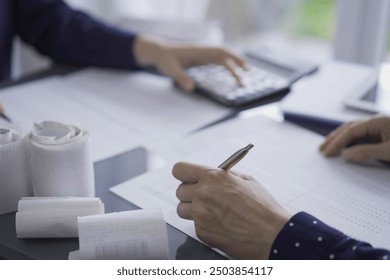 Two accountants or auditors reviewing financial data in office. Professionals analyzing paper reports and using calculators. Audit and taxes in business - Powered by Shutterstock