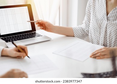Two accountants using a laptop computer for counting taxes at white desk in office. Business Woman pointing into screen with a pen. Teamwork in business audit and finance