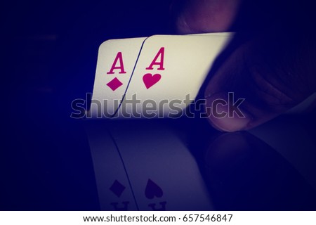 Two aces in the hand the poker player on a black background. Tinted photo in retro style.