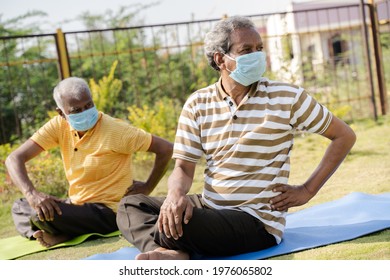 Two Active Senior People With Medical Face Mask Exercising On Yoga Mat During Early Morning - Concept Of New Normal, Elderly Helthcare And Fitness Class At Park During Coronavirus Covid-19 Pandemic