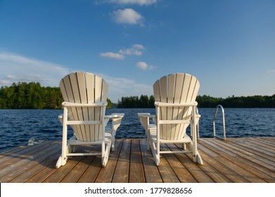 Two Adirondack chairs on a wooden dock overlooking a calm lake in Ontario cottage country. Retirement planning concept.