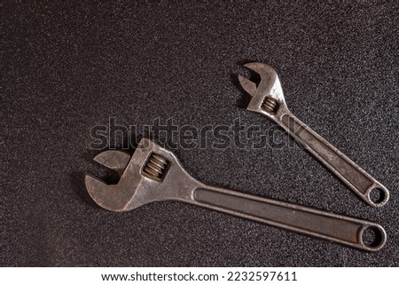 two Adjustable spanner large and small on a black speckled background