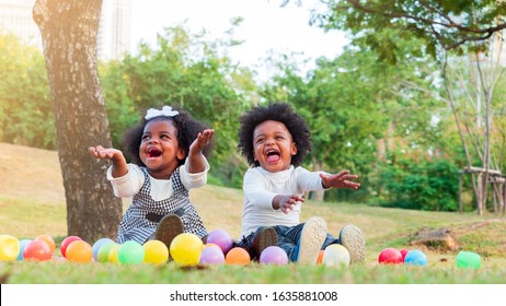 Two adorable African boy and girl laughing with happiness when colorful balls coming down to them.