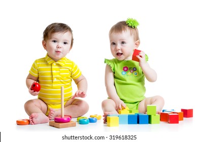 Two adorable babies kids playing with educational toys. Toddlers girl and boy sitting on floor. Isolated on white background.