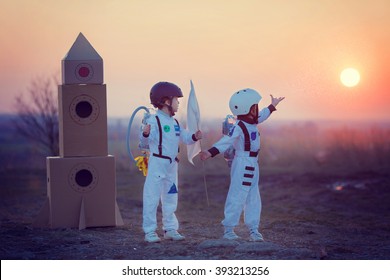 Two adorable children, boy brothers, playing in park on sunset, dressed like astronauts, imagining they are flying on the moon - Powered by Shutterstock