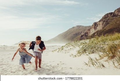 Two adorable children running together at the beach. Brother and sister  playing on the beach. - Powered by Shutterstock