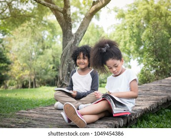 Two Adorable Kids Reading A Book. Cute Friends Playing Together In The Park. Friendship And Education Concept.